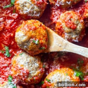 A plate of baked turkey ricotta meatballs with red sauce, garnished with fresh herbs.