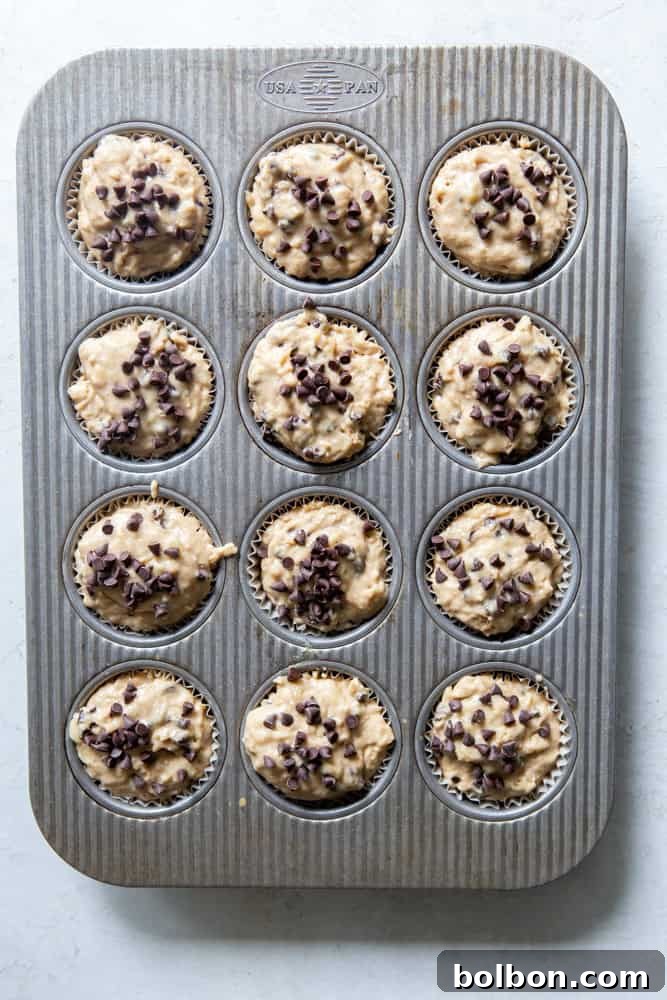 Wholesome Sourdough Banana Muffins 4 Sourdough banana muffin batter scooped into a muffin tin with parchment liners before baking