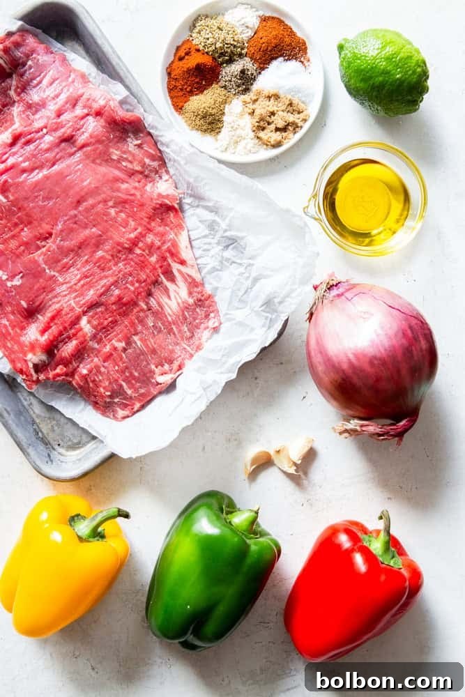 Sheet Pan Steak Fajita Feast 3 Ingredients for steak fajitas laid out: flank steak, a vibrant array of bell peppers (red, yellow, green), red onion, garlic cloves, lime, olive oil, and a blend of aromatic spices.