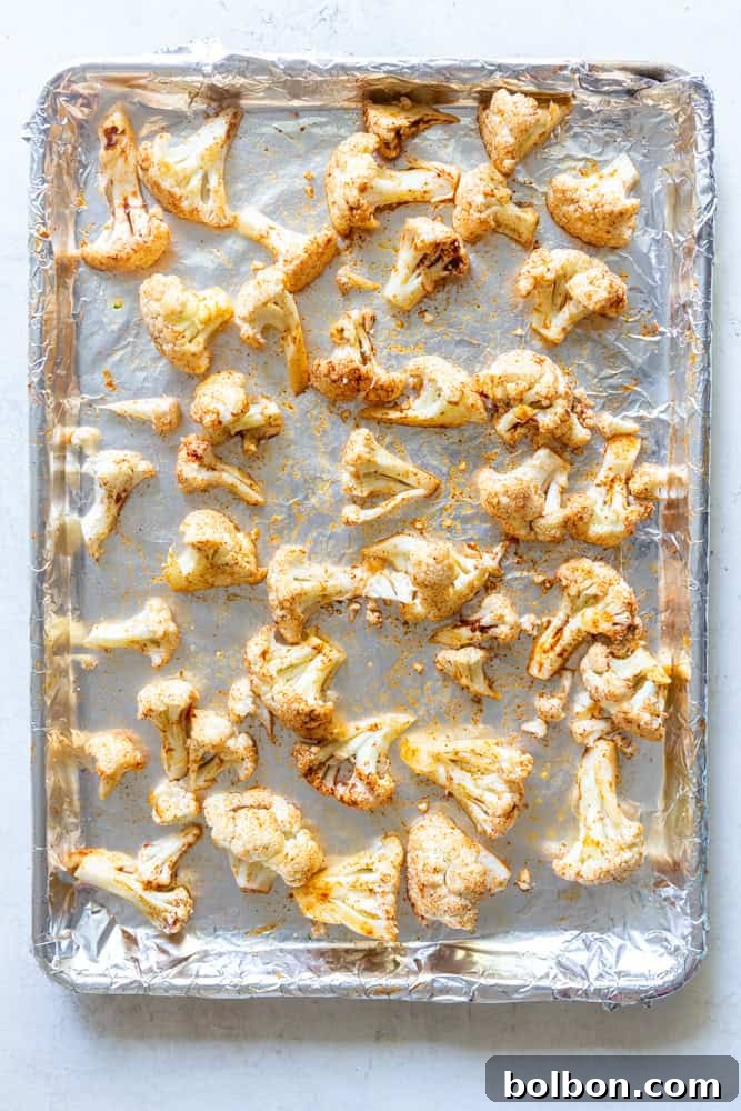 Raw cauliflower florets arranged in a single layer on a baking sheet, ready for roasting.