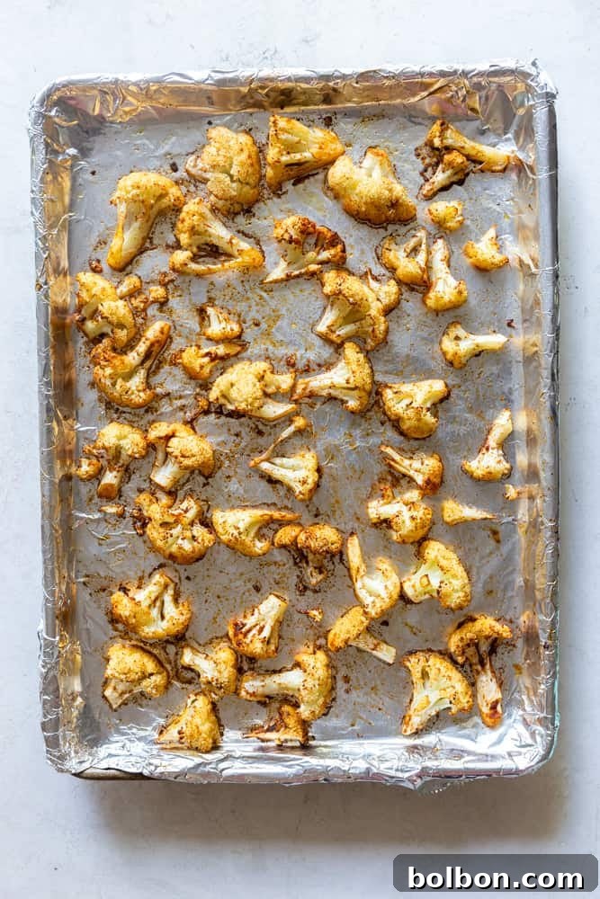 Golden-brown oven roasted cauliflower served on a baking sheet, fresh out of the oven.