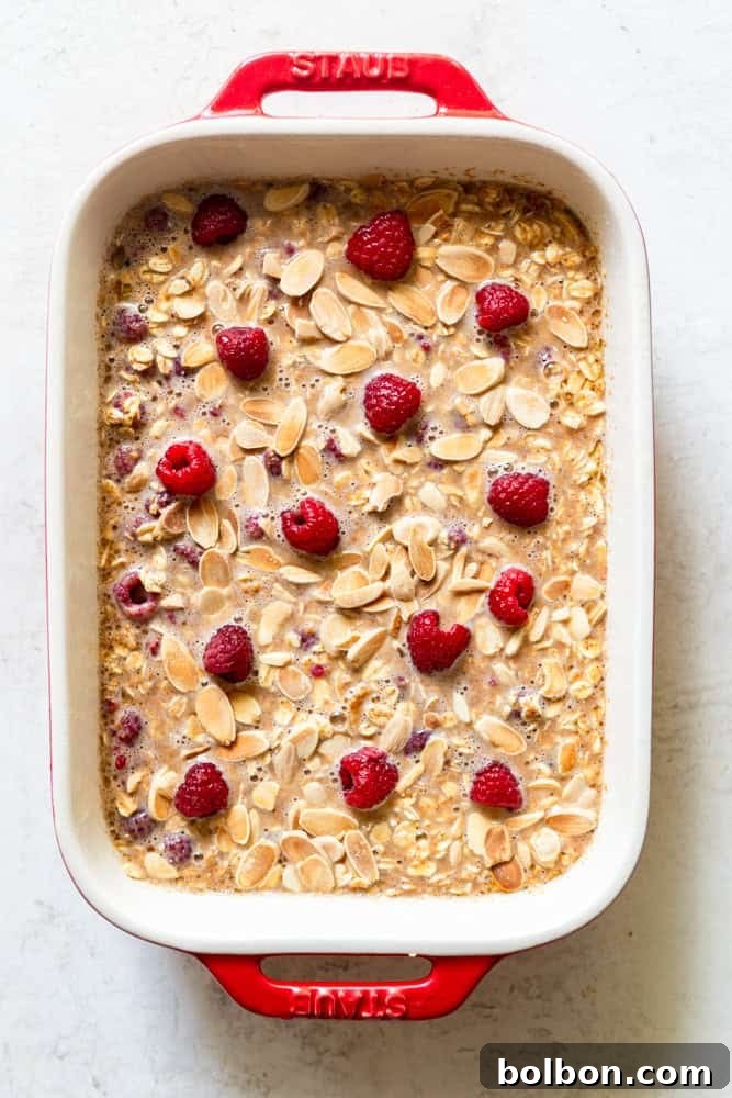 Raspberry Almond oatmeal mixture in a baking dish before being baked, topped with extra raspberries.