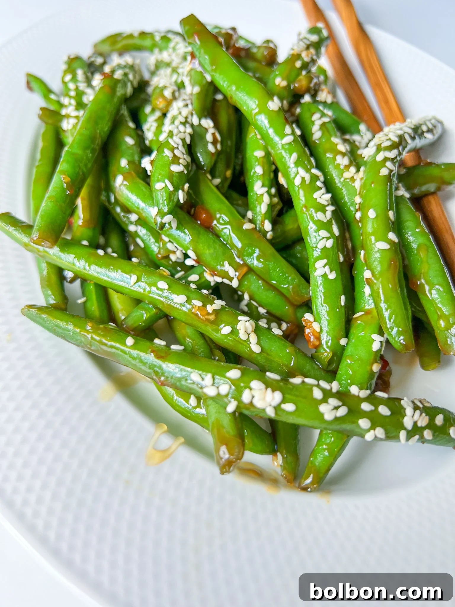 plate of green beans with chopsticks on the side and sesame seeds on top 