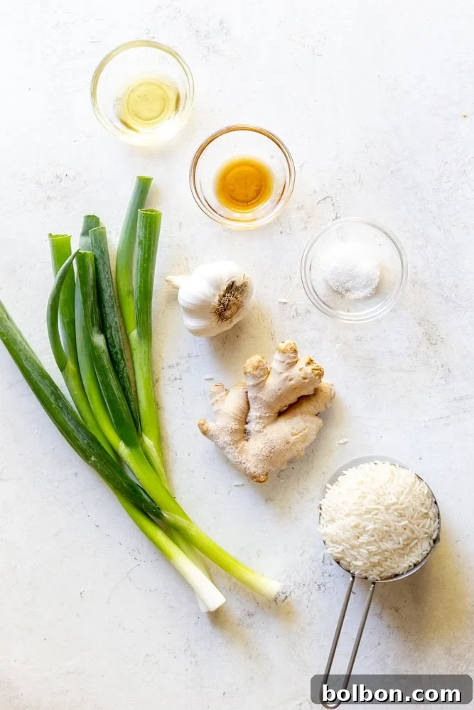 Ingredients for ginger scallion rice laid out: avocado oil, sesame oil, kosher salt, fresh ginger, garlic cloves, jasmine rice, and green onions.