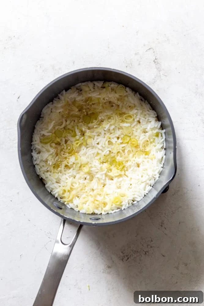 Freshly cooked ginger scallion rice in a pot, fluffy and ready to be served, garnished with green scallion tops.