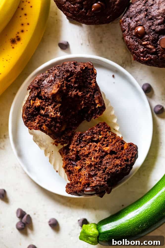 A healthy chocolate zucchini muffin split in half, revealing its moist, tender interior and chocolatey goodness.