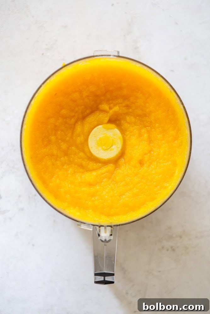Smooth, vibrant homemade pumpkin puree whirling in a food processor, ready for use in delicious recipes.