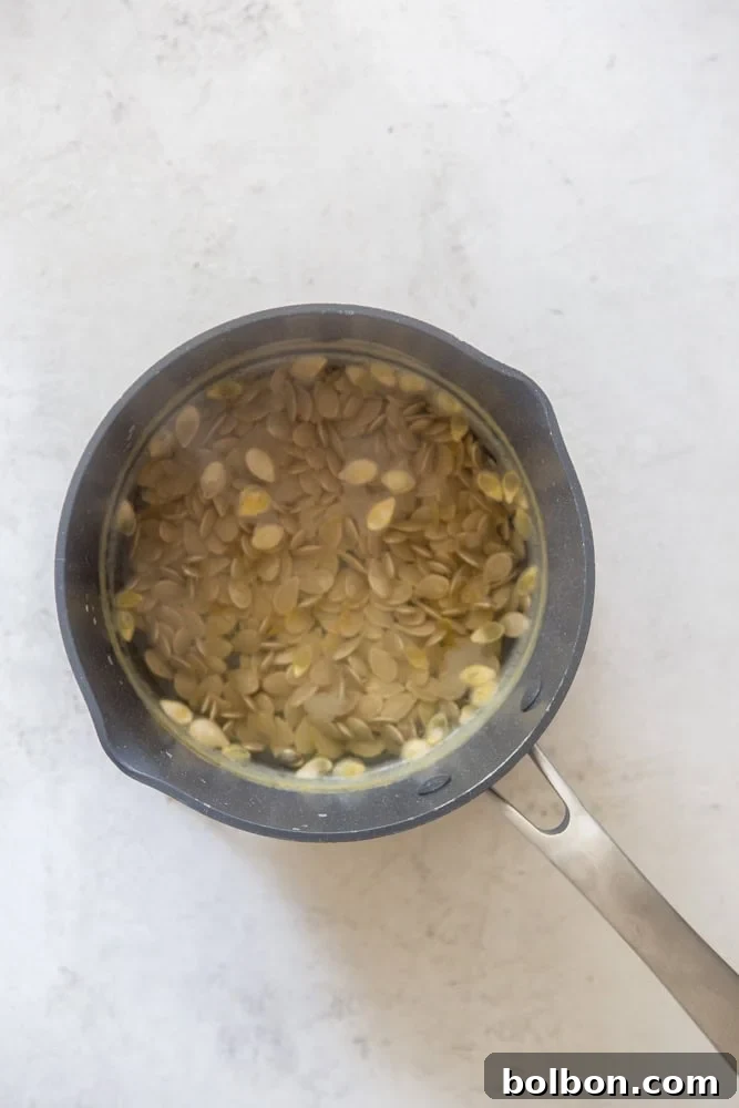 Crispy Roasted Pumpkin Seeds 5 Pumpkin seeds boiling in a saucepan of salted water on the stove.
