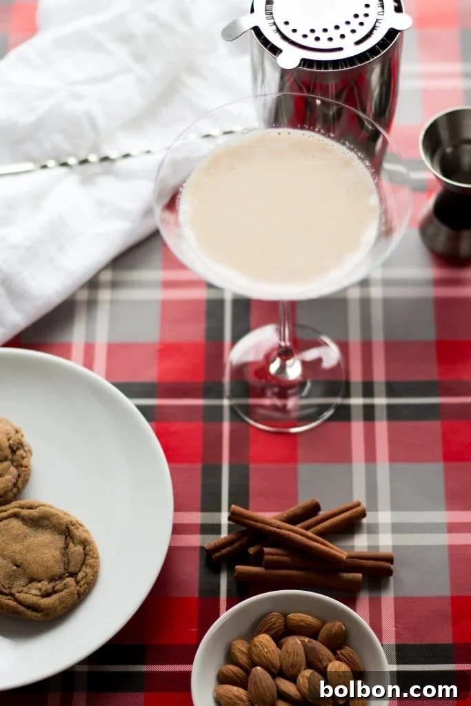 Gingerbread Martini Melodies 3 Hand holding a Gingerbread Martini against a blurred festive background, showcasing its creamy texture and fresh nutmeg garnish.