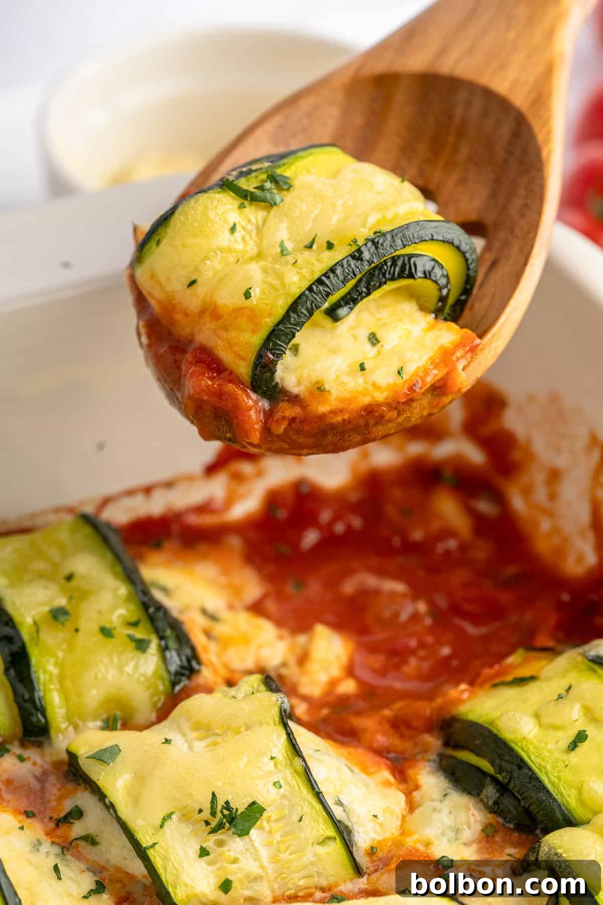 Baking dish full of zucchini lasagna rolls, fresh from the oven with melted cheese. 