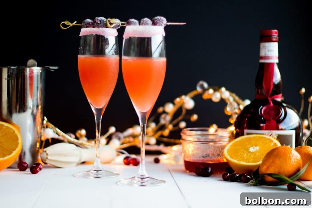 A beautifully presented Cranberry Orange Cosmo, garnished with a sprig of sugared cranberries, ready for festive gatherings.