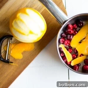 Homemade cranberry orange syrup, a key ingredient for festive cocktails and mocktails, shown in a glass jar.