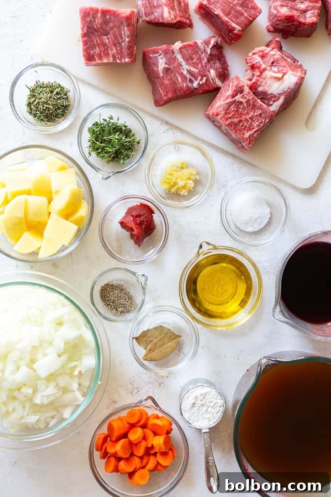 Key ingredients for an authentic Red Wine Beef Stew laid out: succulent chuck roast, fresh onions, potatoes, carrots, a bottle of quality red wine, rich beef broth, aromatic rosemary, thyme, garlic, bay leaf, along with salt, pepper, olive oil, and flour.