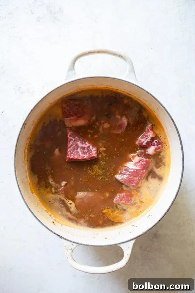 Red Wine Beef Stew in a Dutch oven before cooking, showcasing the beef added without pre-browning, designed to caramelize in the oven's heat.