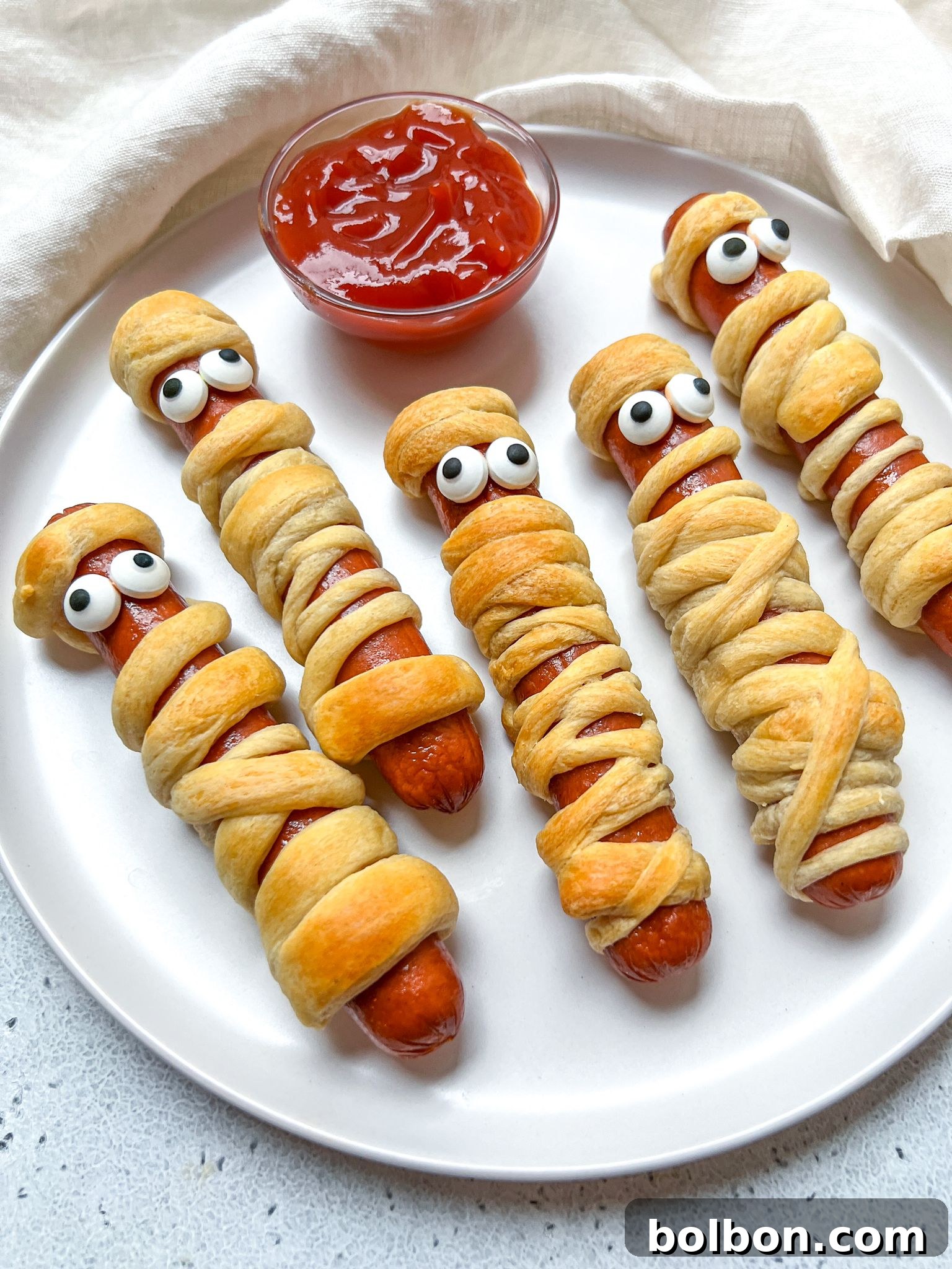 Frankenfurter Mummies 2 A vibrant Halloween Mummy Hot Dogs platter, featuring creatively wrapped sausages with dough