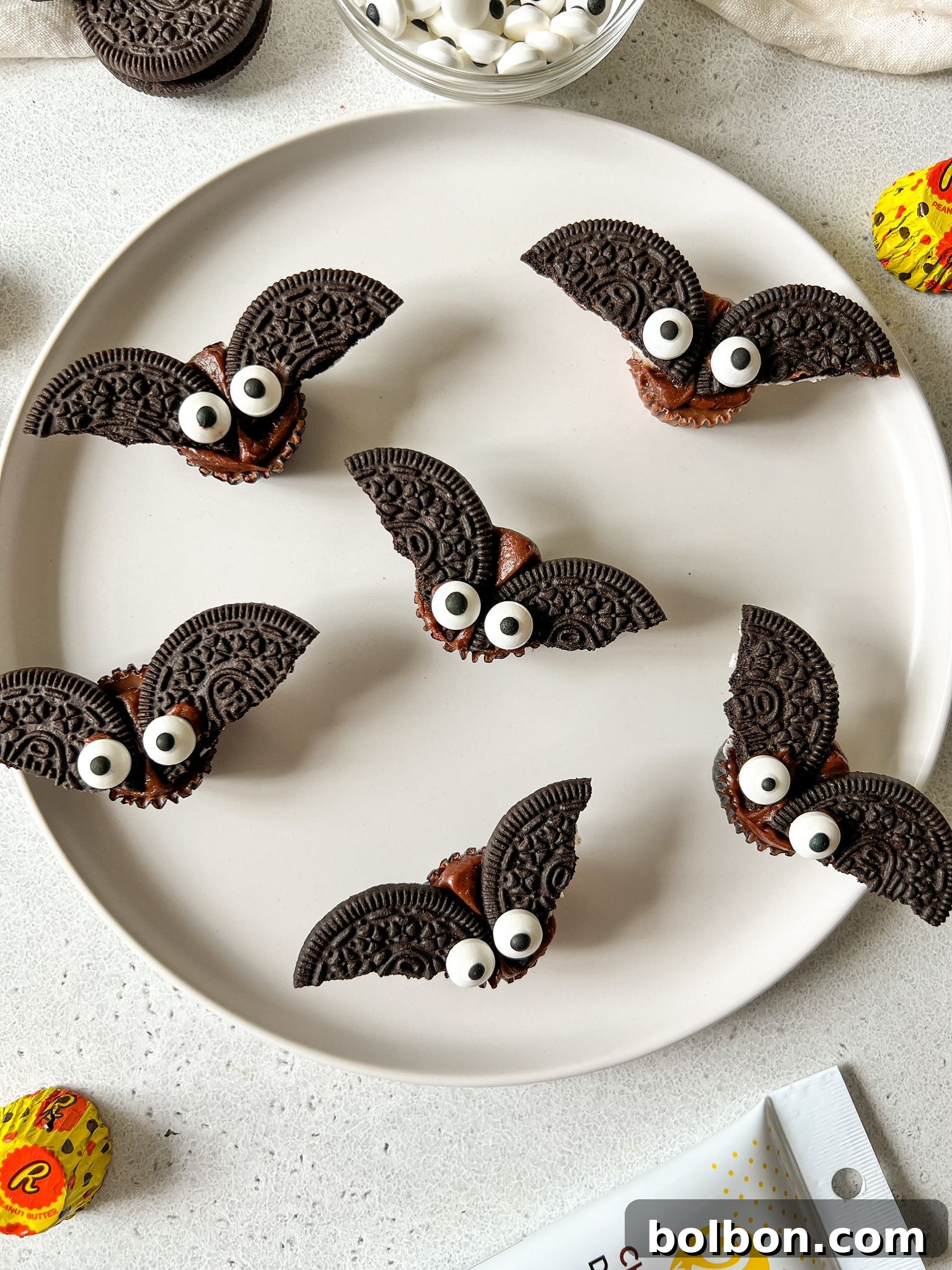 Frightfully Delicious Chocolate Bats 2 A close-up shot of several completed Halloween Chocolate Bats, made from Reese's Cups and Oreo cookies, displayed on a clean white surface with a subtle shadow.