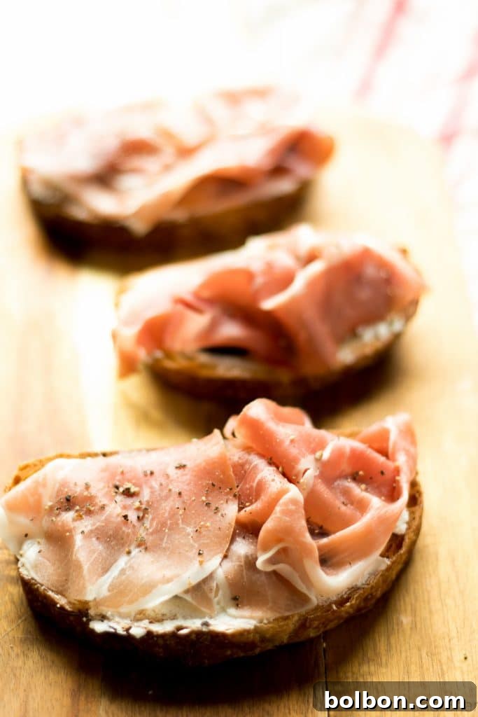 Fig, Prosciutto, and Creamy Chèvre Crostini 4 Artfully arranged Fig, Goat Cheese, and Prosciutto Bruschetta on a wooden board