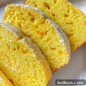 Zesty Orange Lemon Delight 3 Three slices of moist Orange Lemon Cake with a light dusting of powdered sugar on top, arranged on a white plate. The cake appears soft and fluffy, with a slightly golden crust.