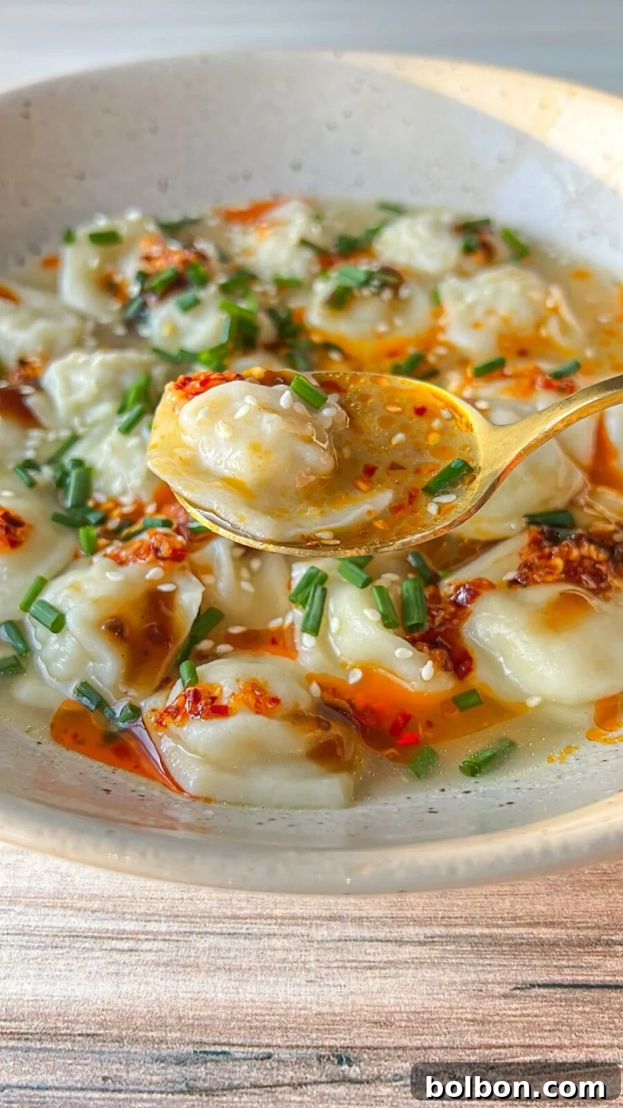 A steaming bowl of 10-minute dumpling soup, garnished with fresh scallions and a drizzle of chili oil.