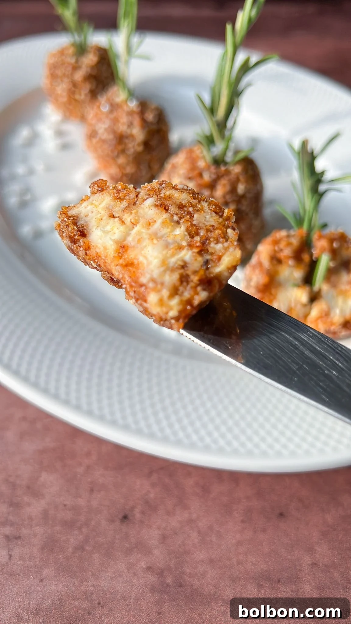 Hazelnut Cheese Balls garnished with rosemary, served on a white plate