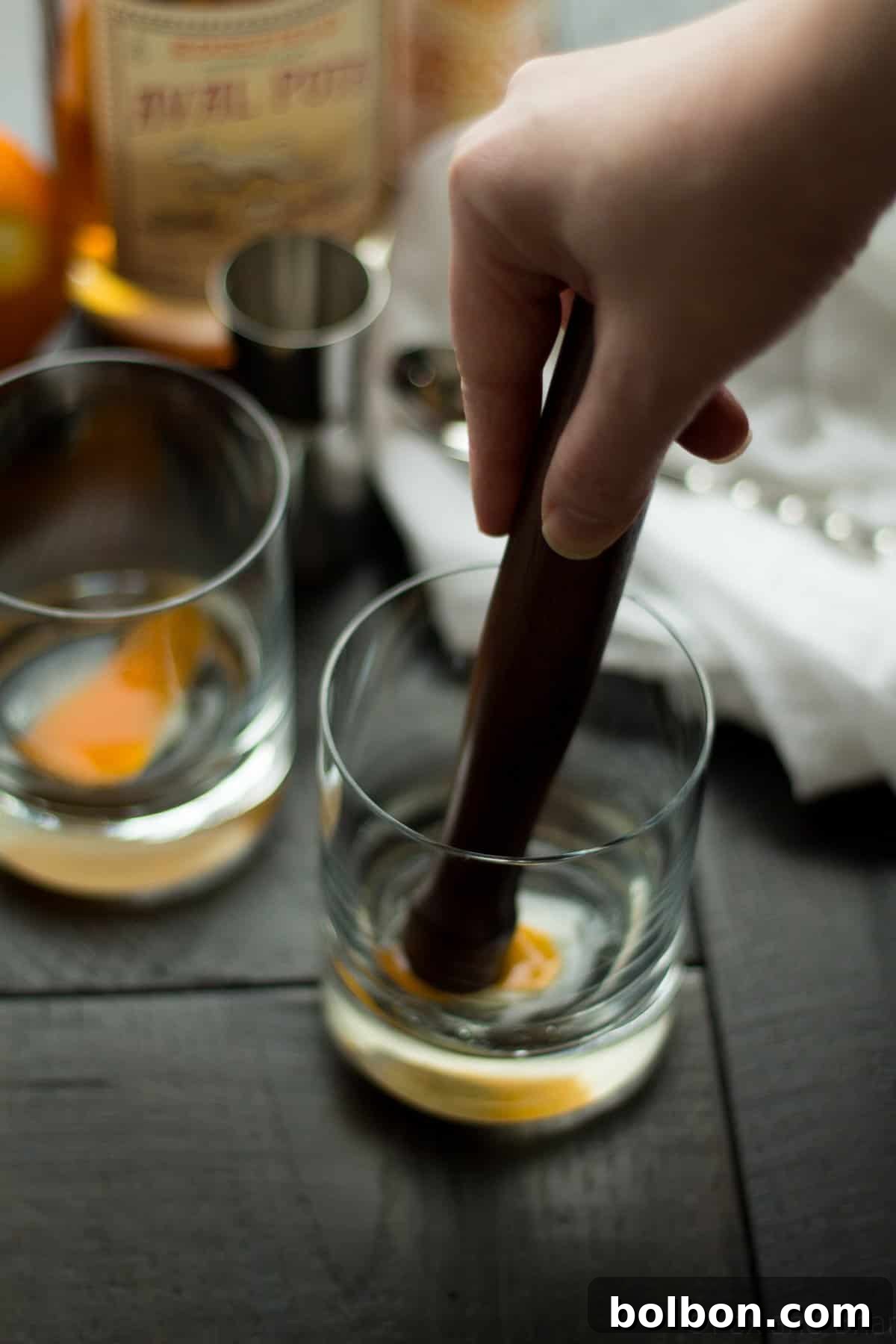 A freshly muddled Apple Old Fashioned base with ice, awaiting the final pour of apple whiskey, showcasing the texture and vibrant color.