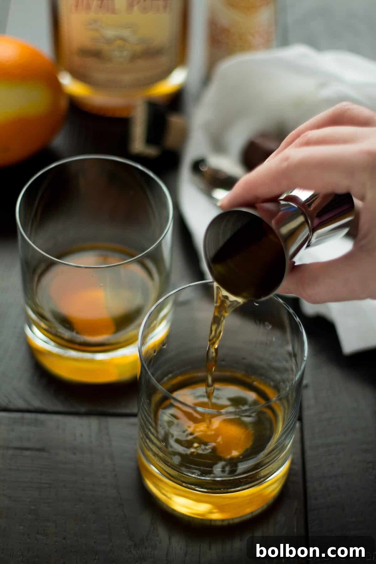 The Apple Old Fashioned ready to be served, with an orange peel artfully draped over the ice, highlighting the rich liquid.