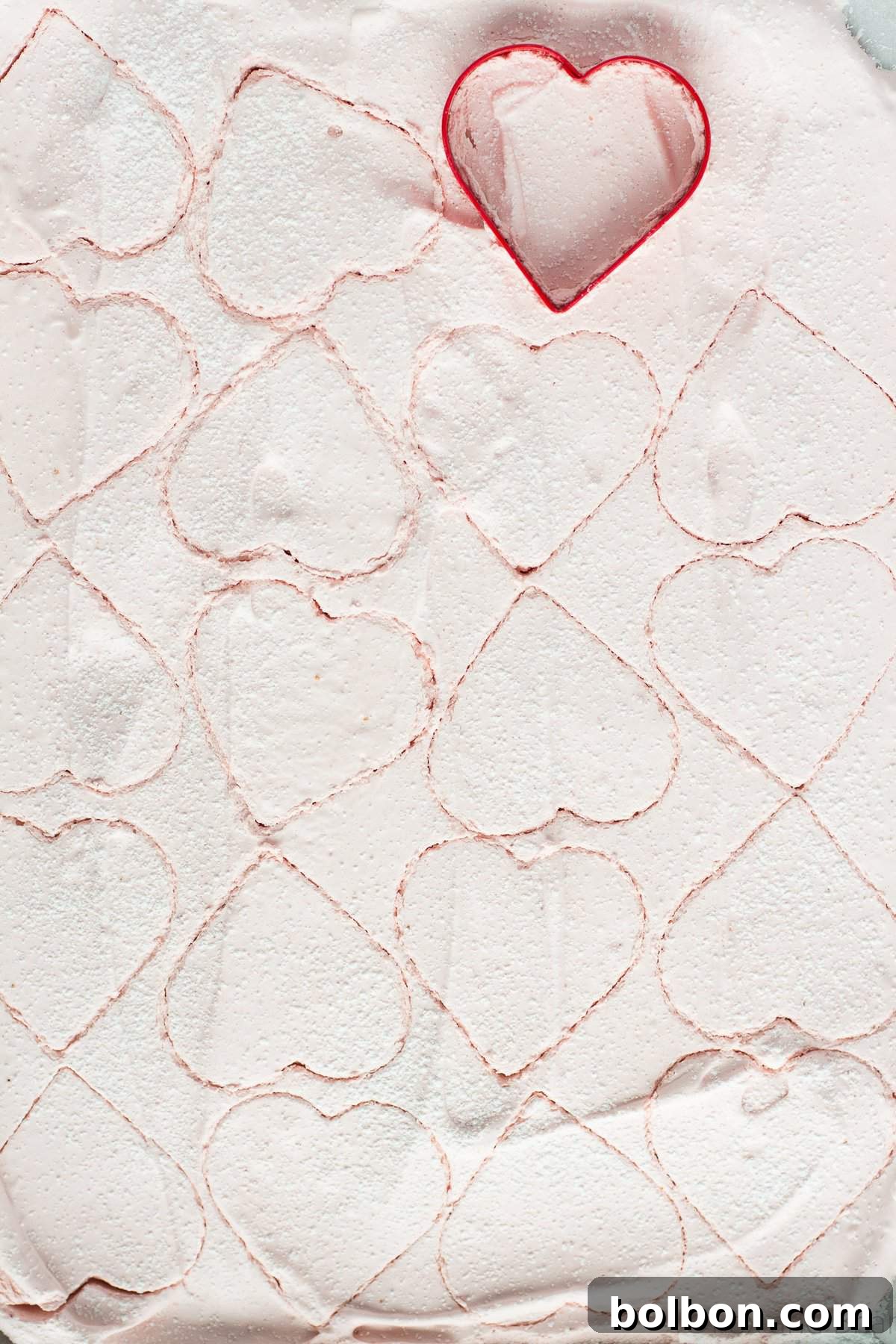 Close-up of a homemade strawberry marshmallow cut into a heart shape, showcasing its delicate pink hue and soft texture.