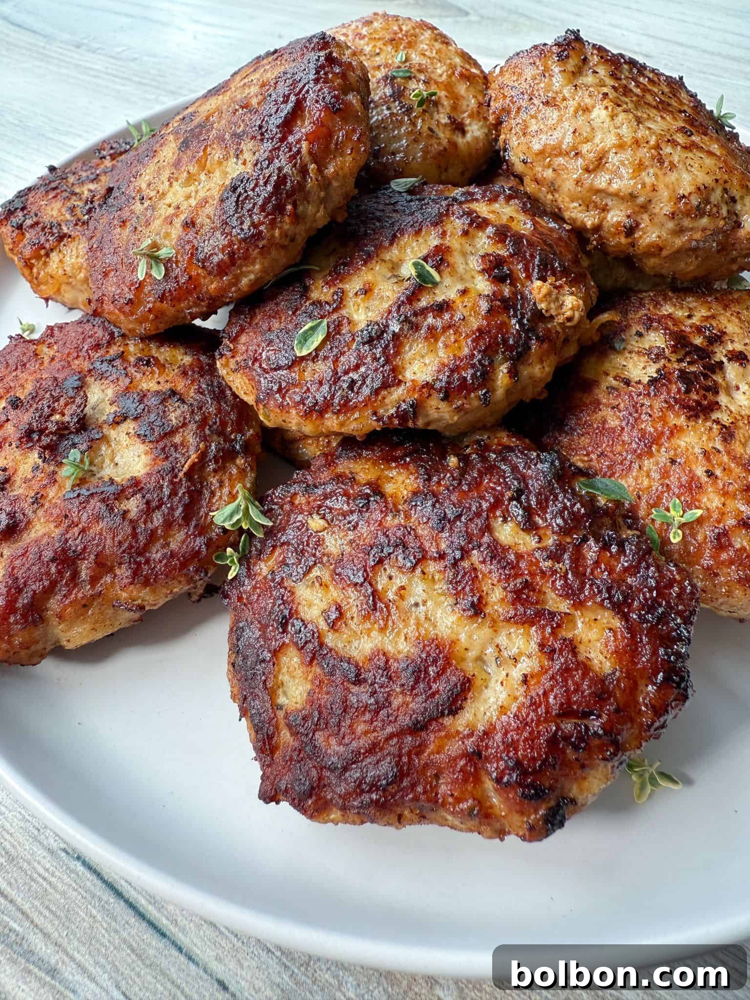 Easy meatball recipe. A plate of browned chicken patties garnished with fresh herbs.