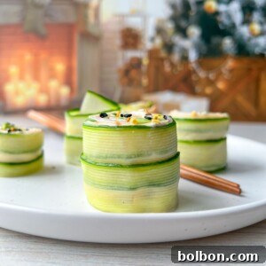 A white plate with neatly stacked Cucumber and Avocado Rolls garnished with sesame seeds, set on a light wooden table. In the blurred background, a decorated Christmas tree and cozy fireplace with stockings and candles add festive warmth.