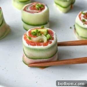 Chopsticks hold a Salmon Cucumber Roll filled with cream cheese and smoked salmon on a white plate, surrounded by similar rolls garnished with chopped green herbs, highlighting a fresh, healthy recipe.