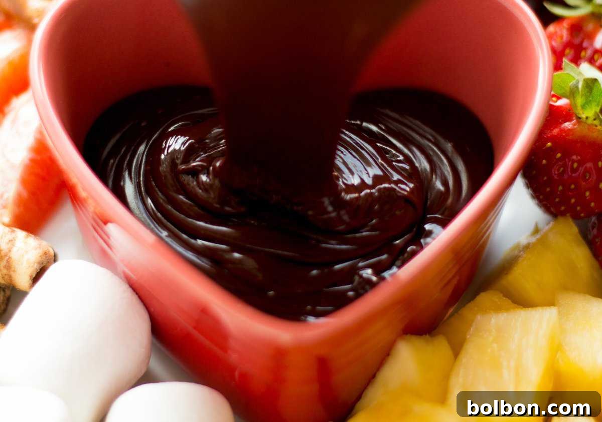 Melted dark chocolate and half and half being whisked together in a double boiler for a smooth, creamy fondue base.