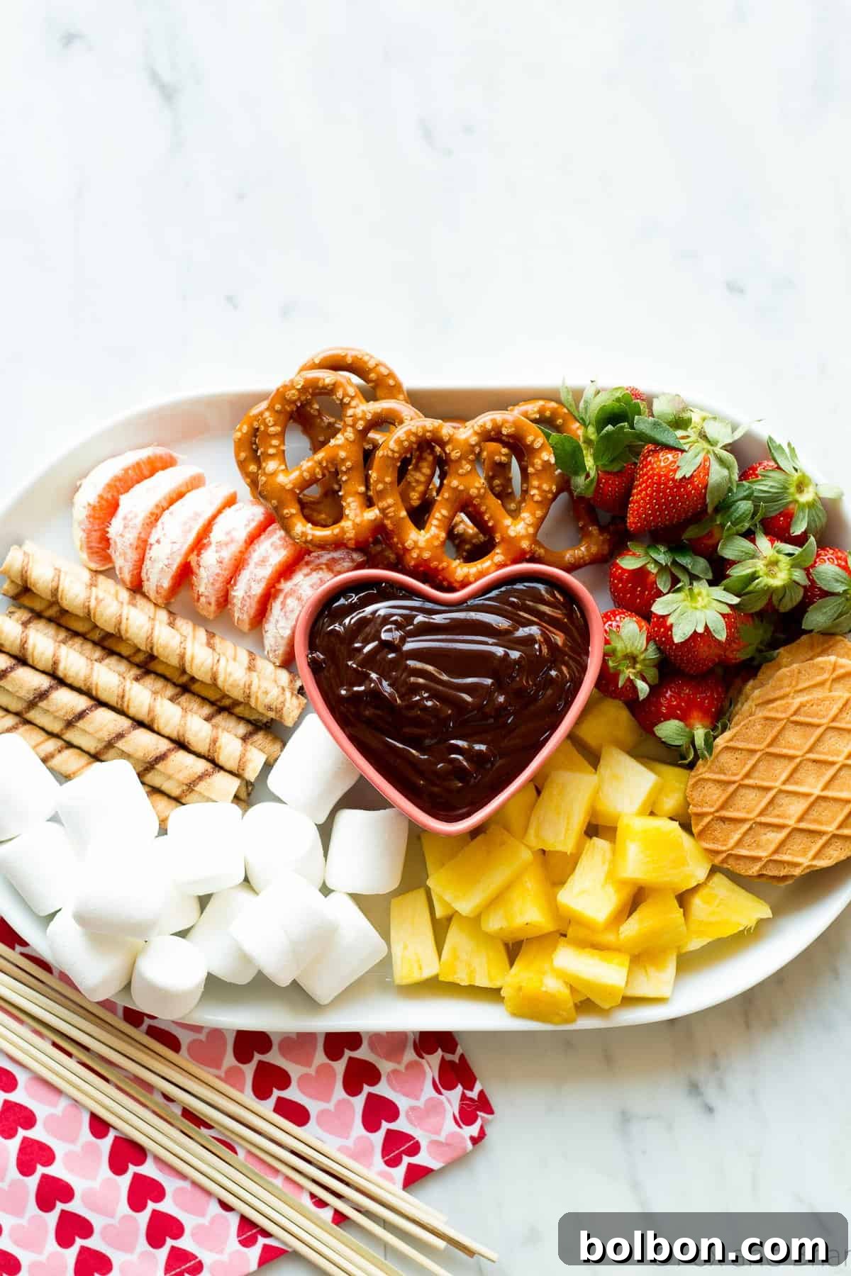 Easy chocolate fondue served in a simple white ceramic dish, with fresh fruit dippers, demonstrating no fondue pot is needed.
