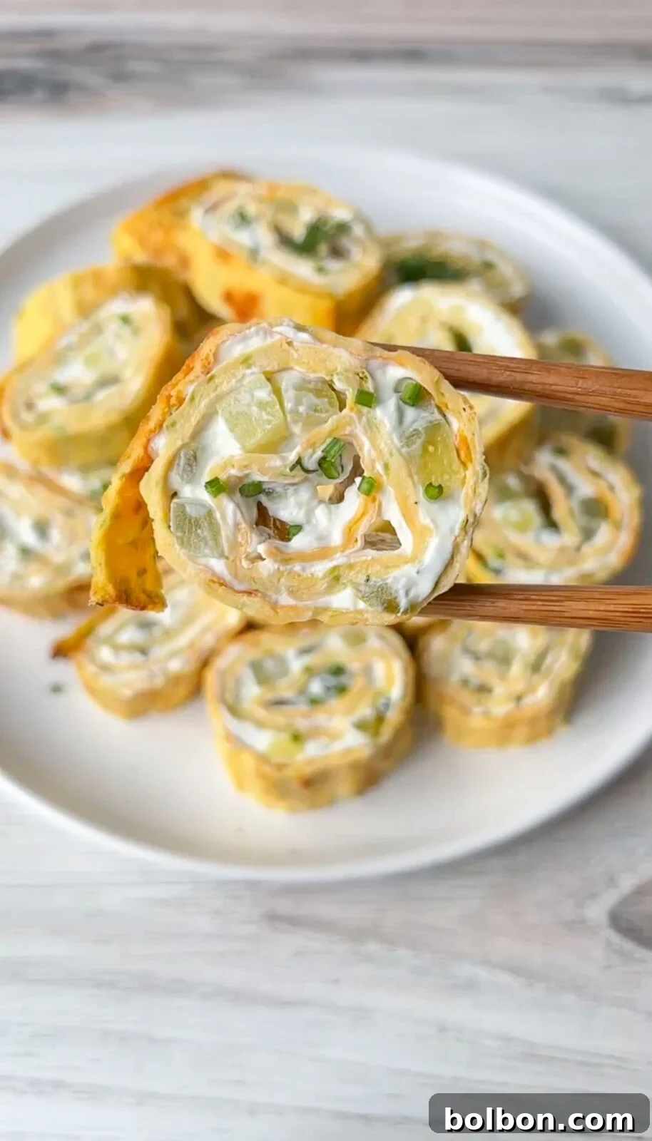 Zucchini Egg Roll pinwheels filled with creamy dip, garnished with fresh herbs.