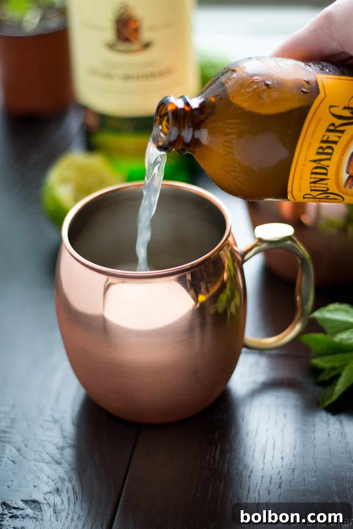 Emerald Kick 4 Ingredients for an Irish Mule laid out: bottle of whiskey, limes, and ginger beer.