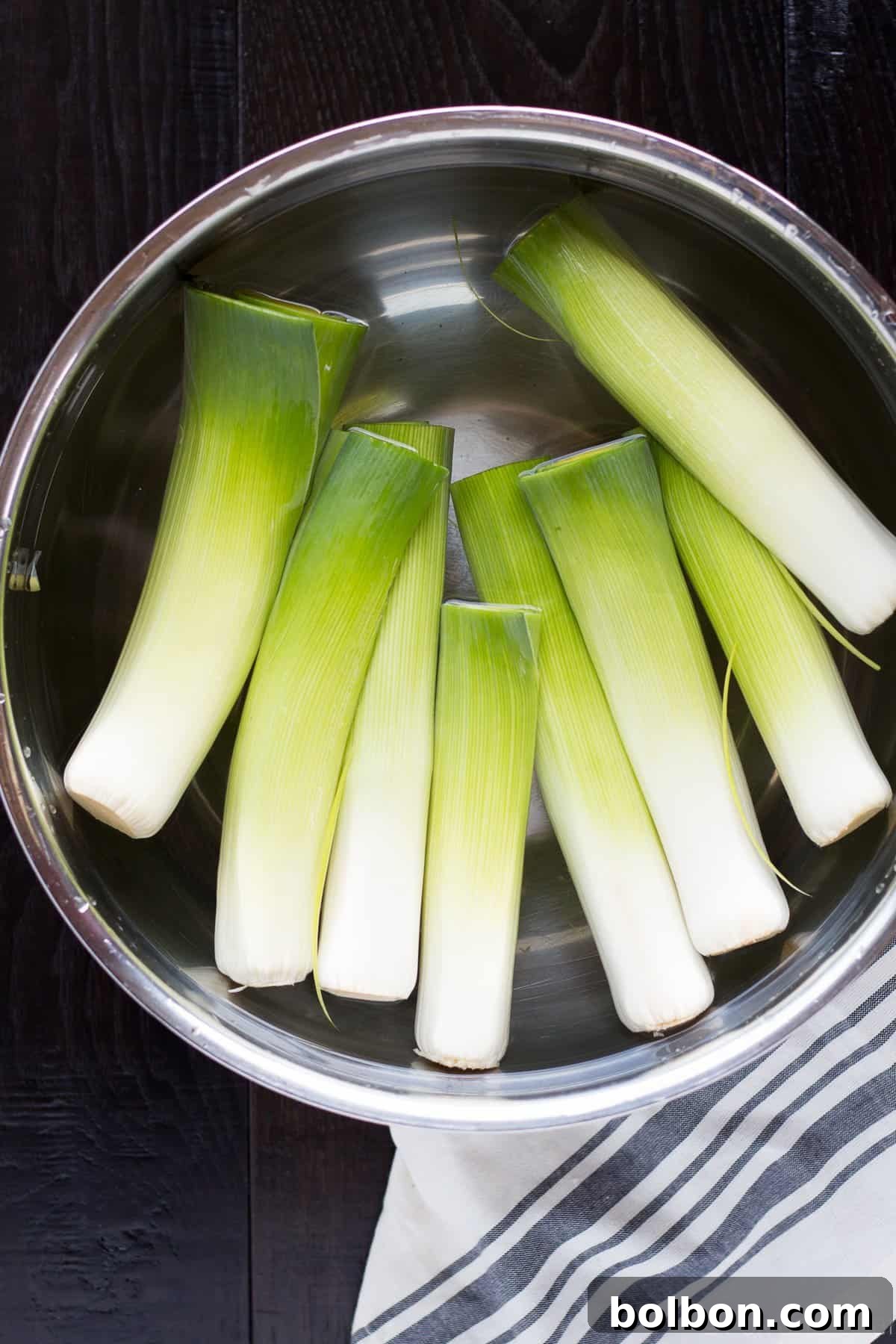 Velvety Braised Leeks 4 Four leek halves laid flat in a non-stick skillet, expertly caramelized to a rich golden hue before braising.