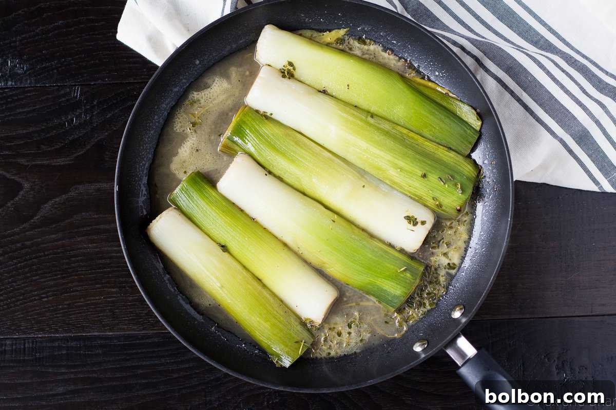Velvety Braised Leeks 6 A skillet with caramelized leeks simmering in a luscious white wine and broth sauce, covered to tenderize.
