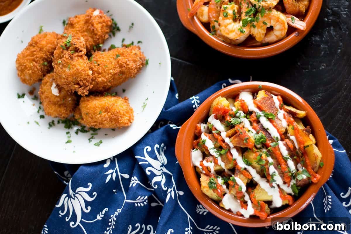 Ultimate Patatas Bravas Guide 2 Crispy baked Patatas Bravas with smoky salsa brava and creamy garlic aioli on a rustic white plate.