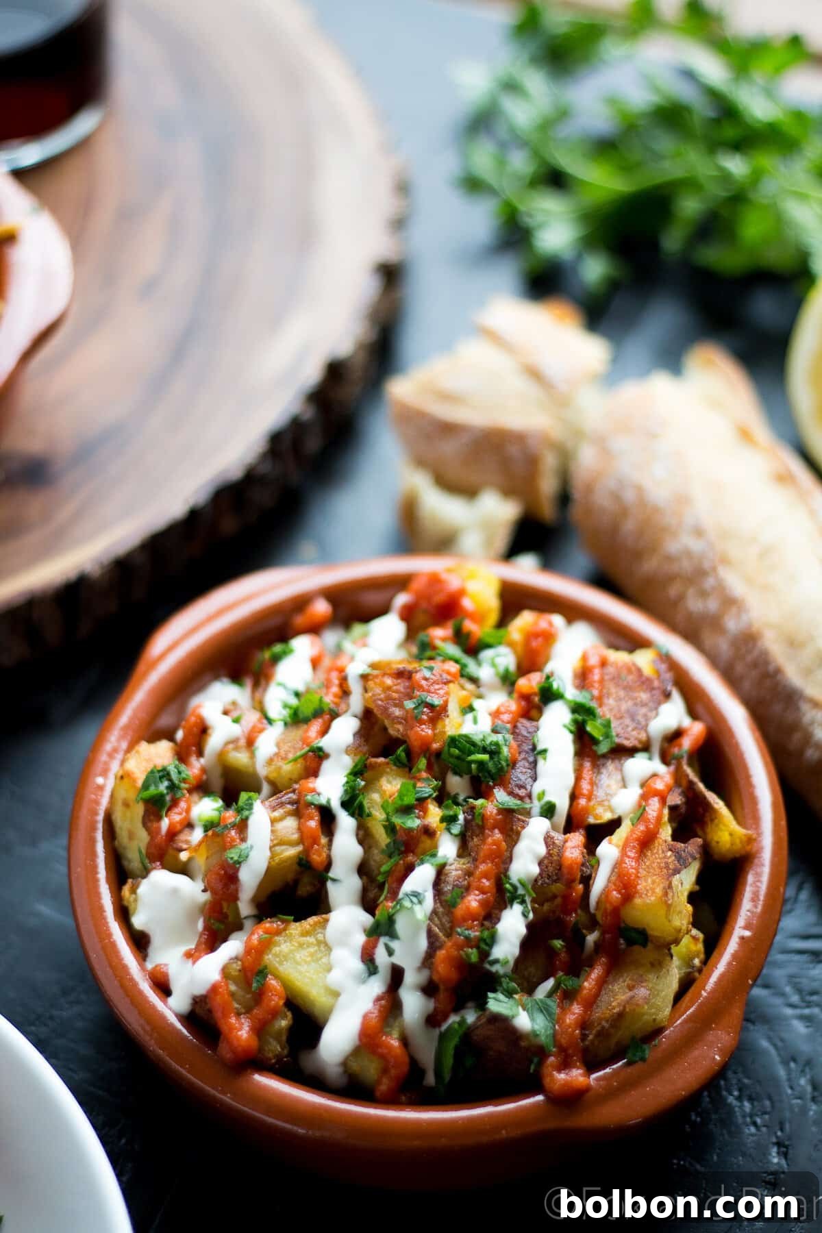 Ultimate Patatas Bravas Guide 3 Close-up of baked Patatas Bravas, showing their golden, crispy exterior, drizzled with red salsa brava.