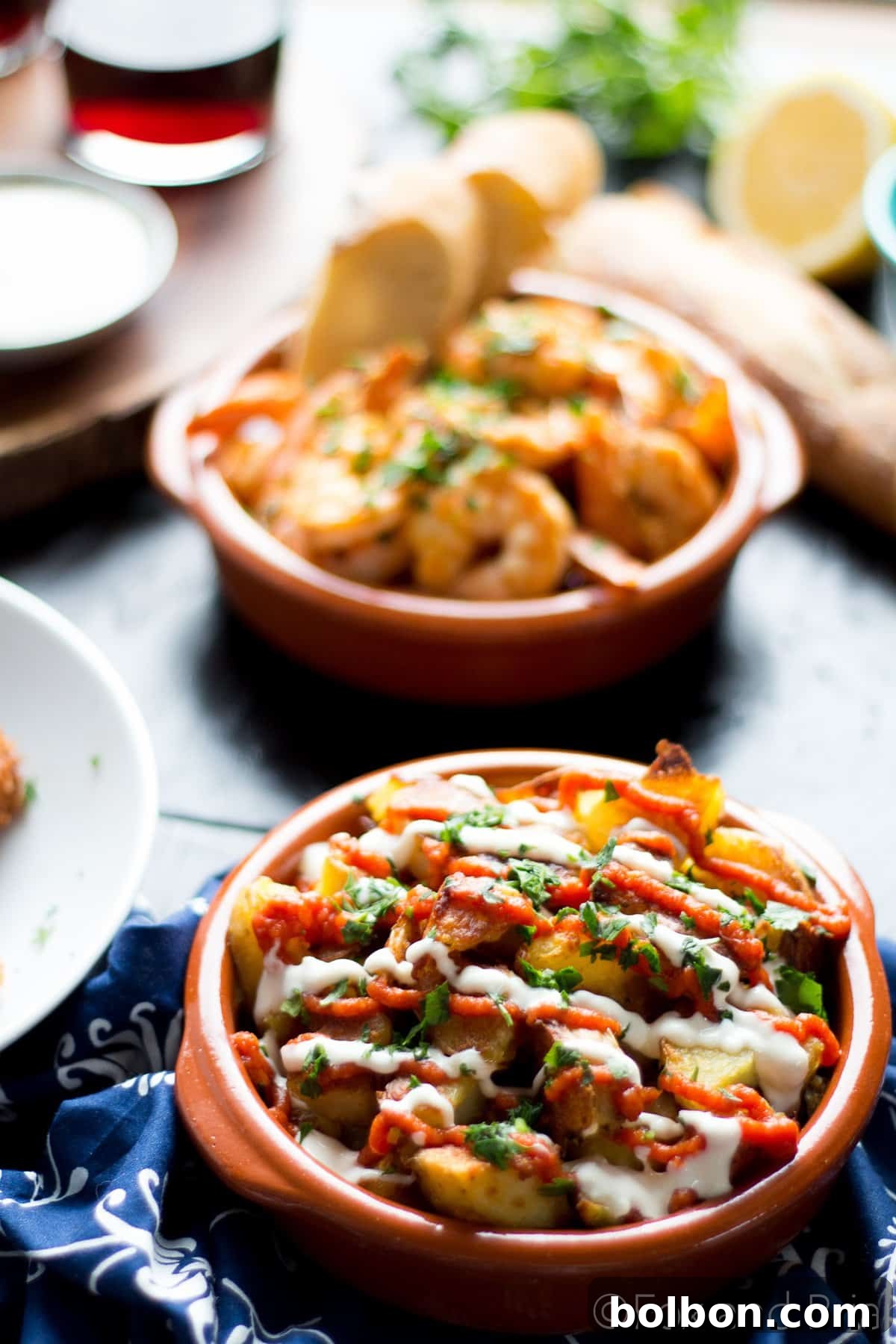 Ultimate Patatas Bravas Guide 5 Hands reaching for a plate of freshly baked, crispy Patatas Bravas, highlighting the golden brown texture.
