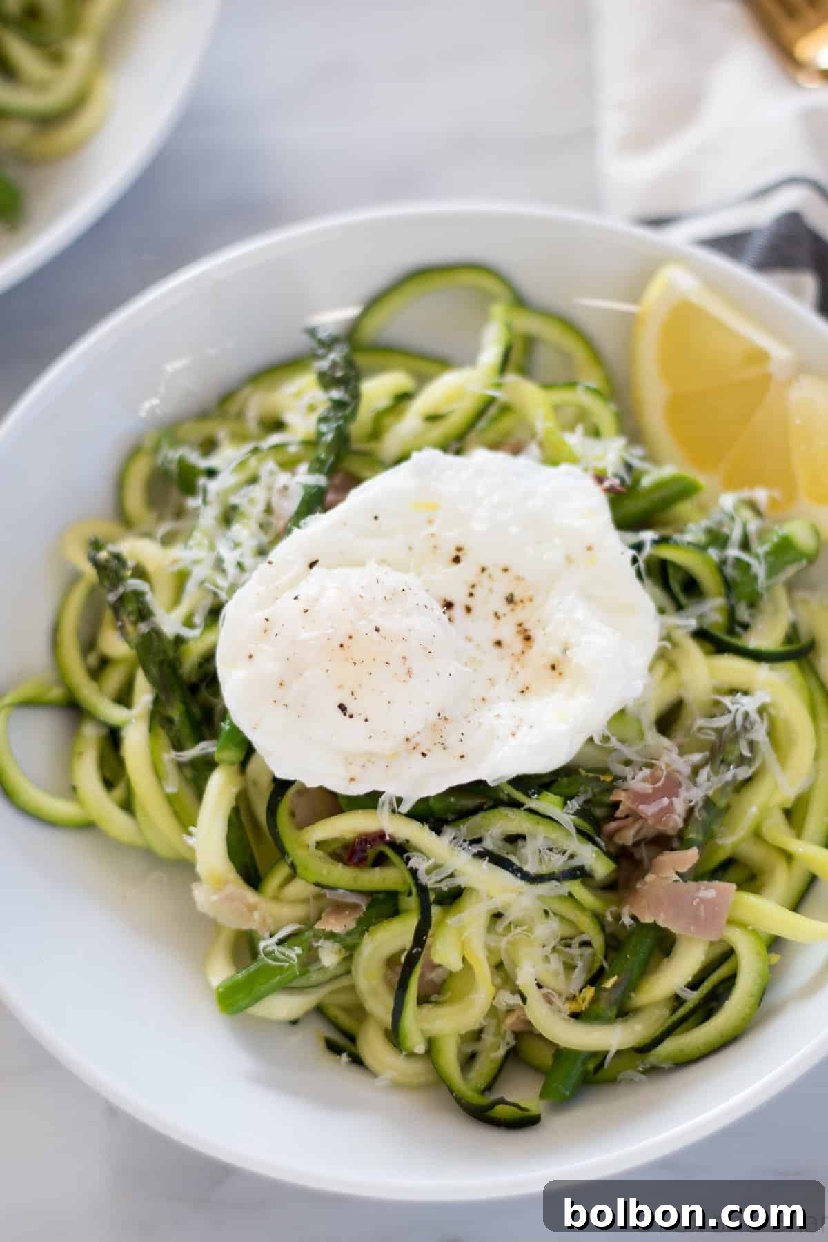 Zoodles (zucchini noodles) quick cooked with asparagus, prosciutto, parmesan cheese, lemon and white wine all topped with a poached egg make a quick and light spring meal.