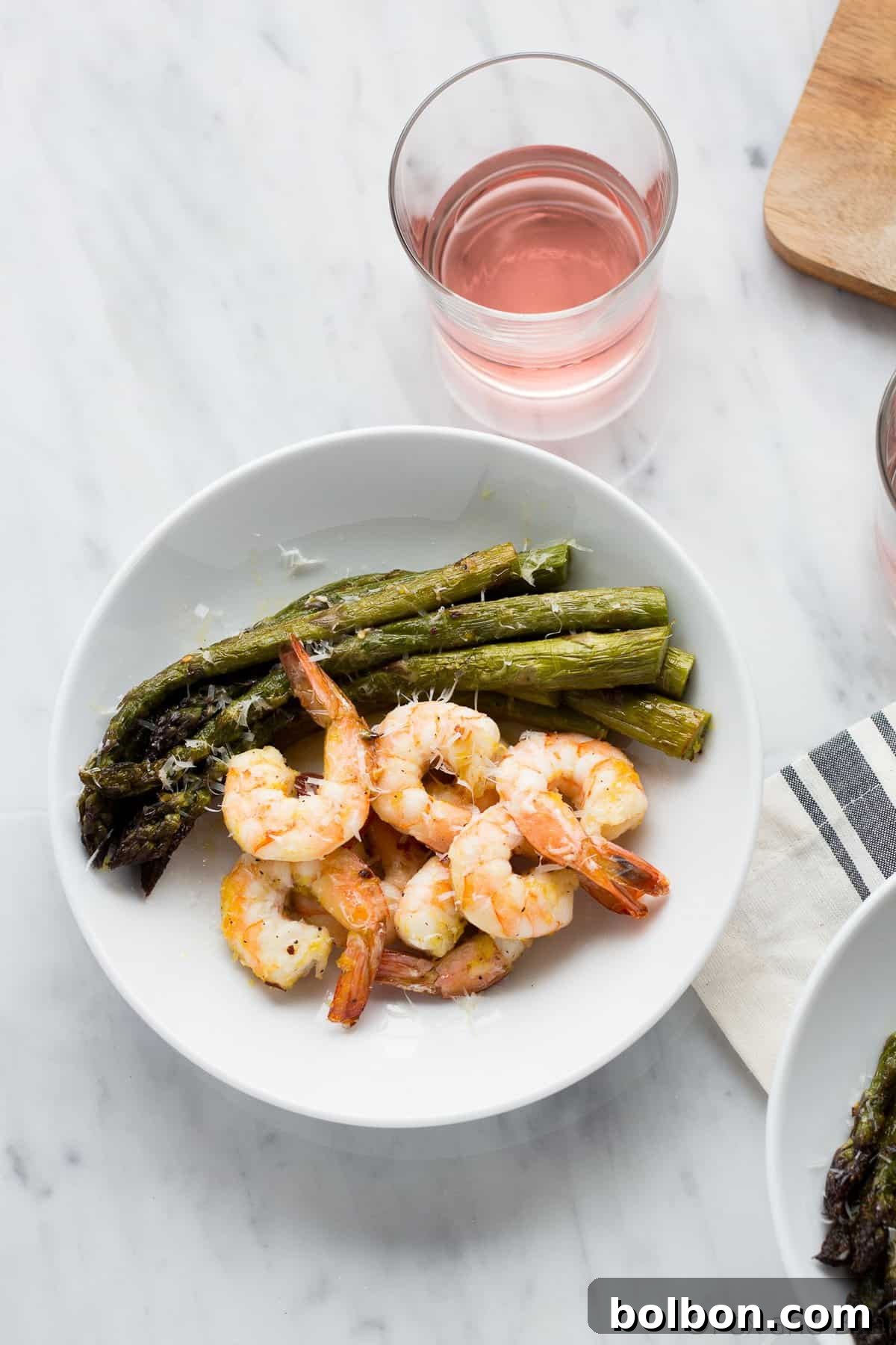 A vibrant display of cooked shrimp and asparagus on a baking sheet, seasoned with lemon zest and red pepper flakes.