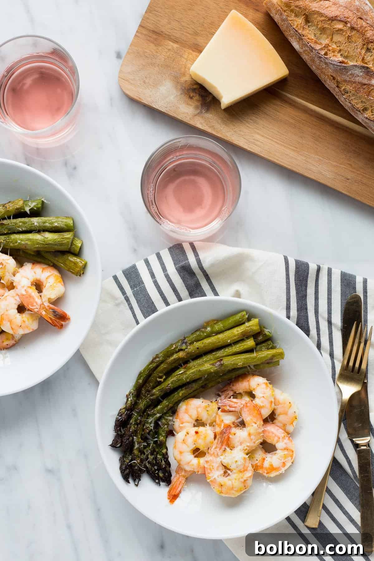 A single serving of roasted shrimp and asparagus, garnished with fresh Parmesan cheese, served with a side of fluffy rice.