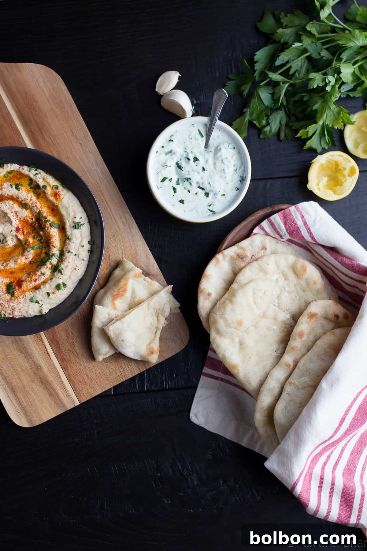 Stack of warm, freshly baked homemade pita bread under a kitchen towel