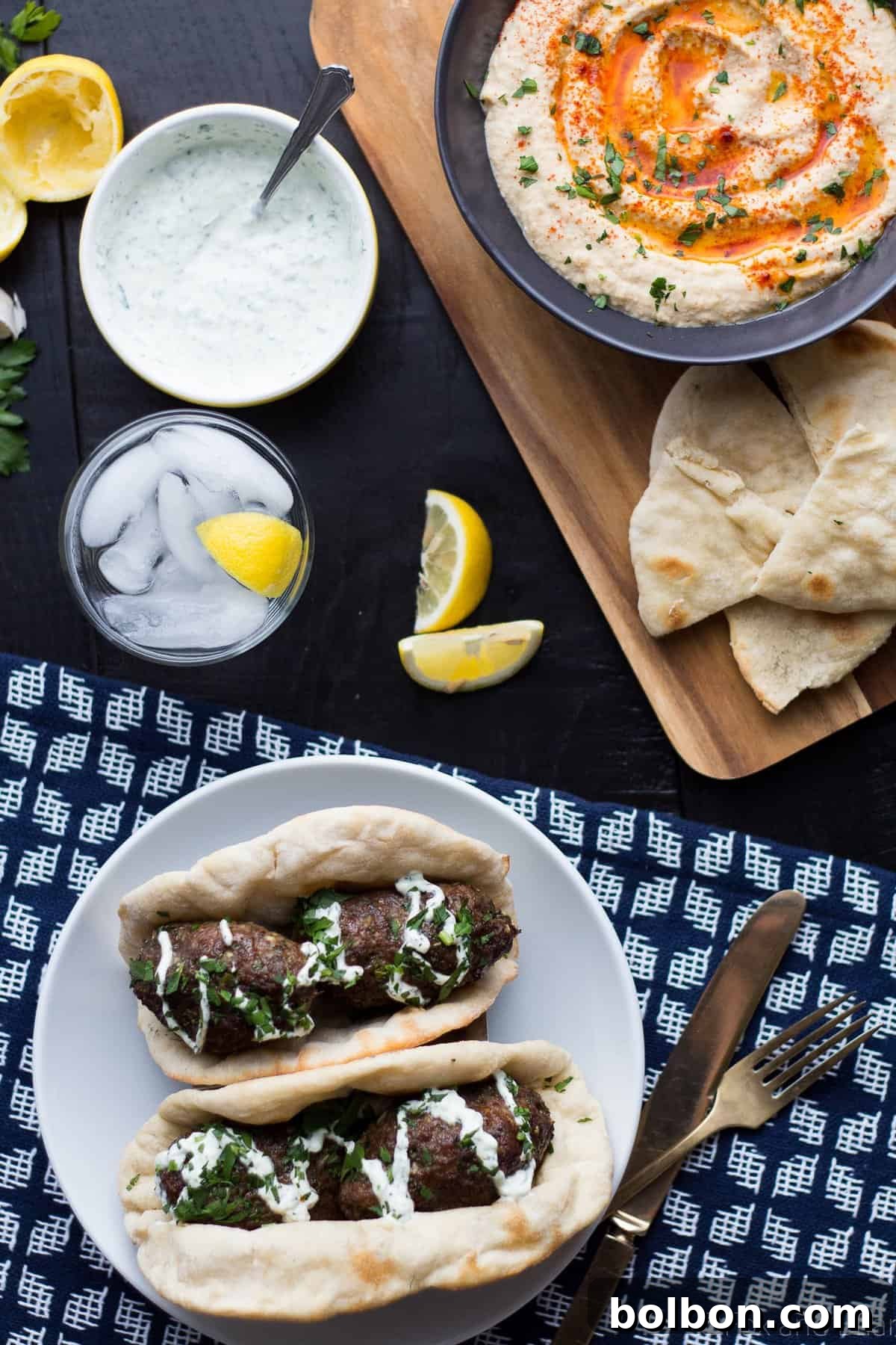 Grilled Lamb Kofta Kebabs served with a creamy mint yogurt sauce and fresh herbs.