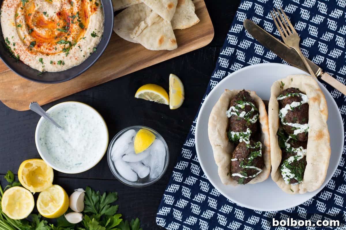 A close-up shot of cooked lamb kofta kebabs, garnished with fresh herbs.