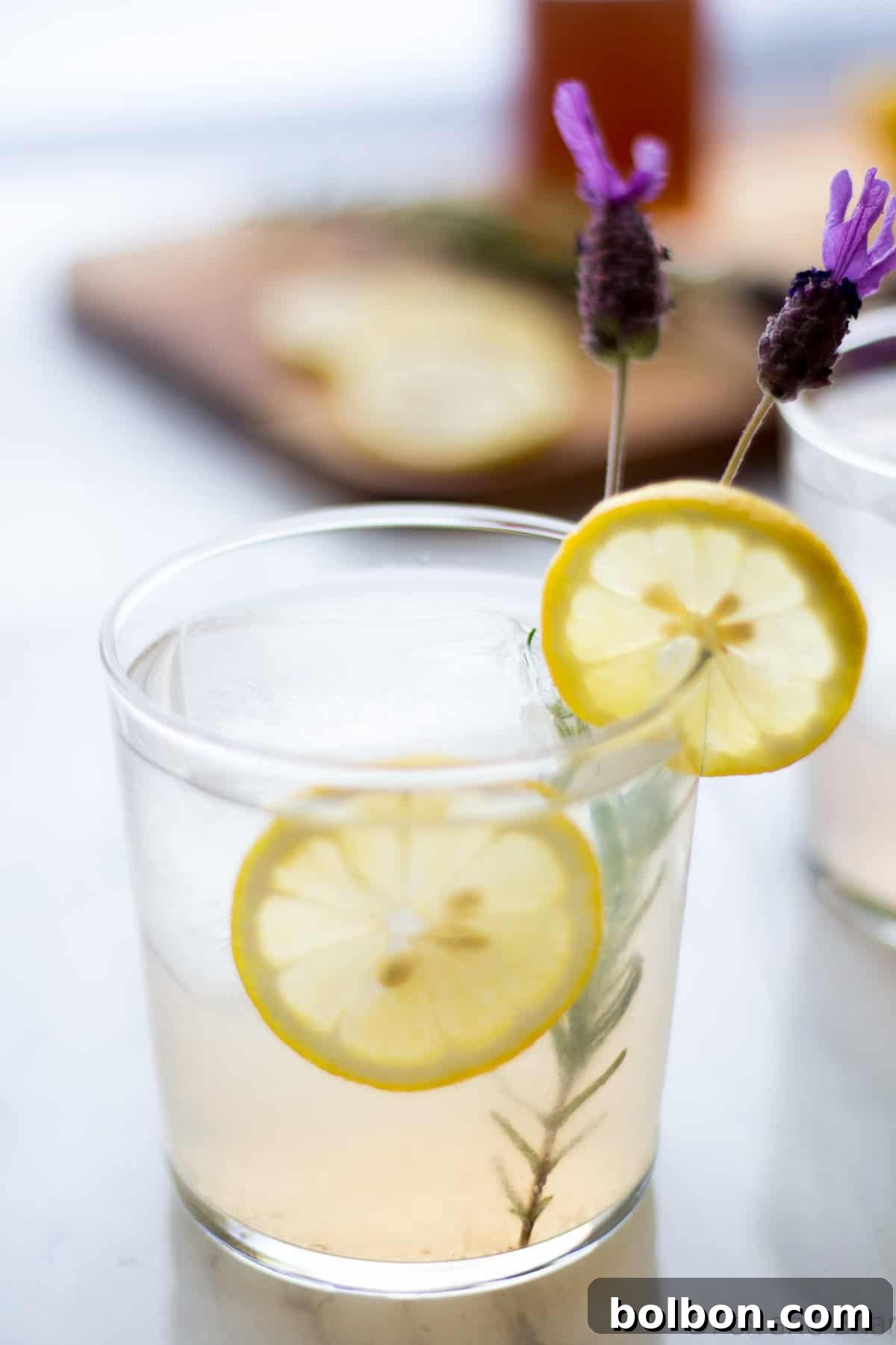 Wild Lavender Collins 6 A refreshing Lavender Collins cocktail in a tall glass, set outdoors on a patio, ready to be enjoyed.