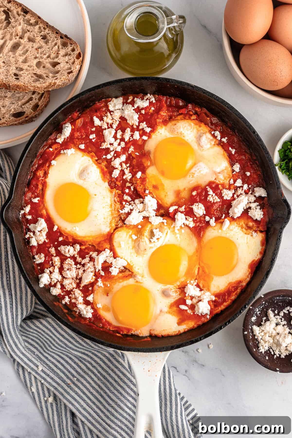 A skillet with sauce, eggs, and feta on top. 