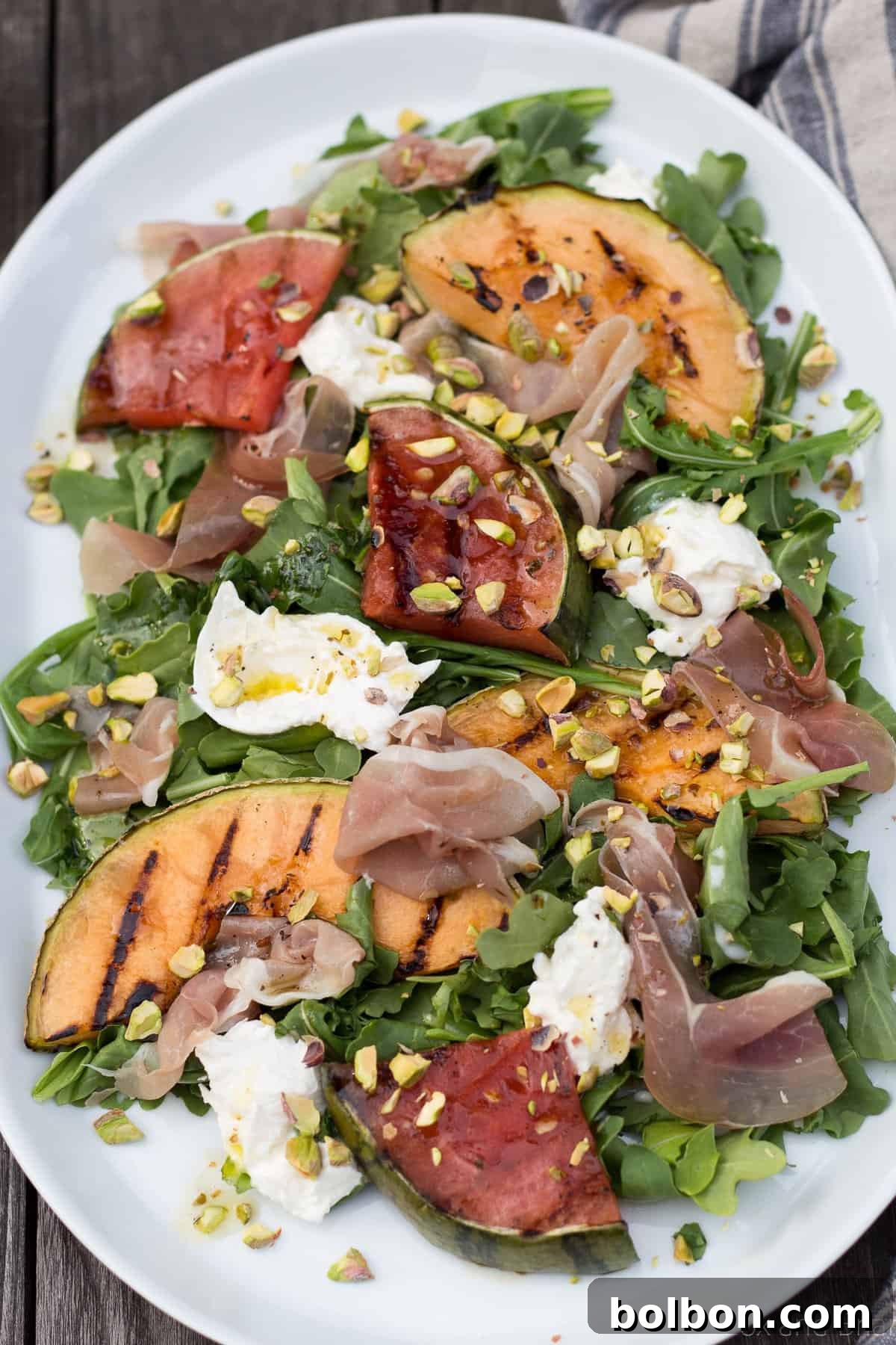 Overhead view of a vibrant Grilled Melon Salad with Prosciutto and Burrata, artfully arranged on a platter