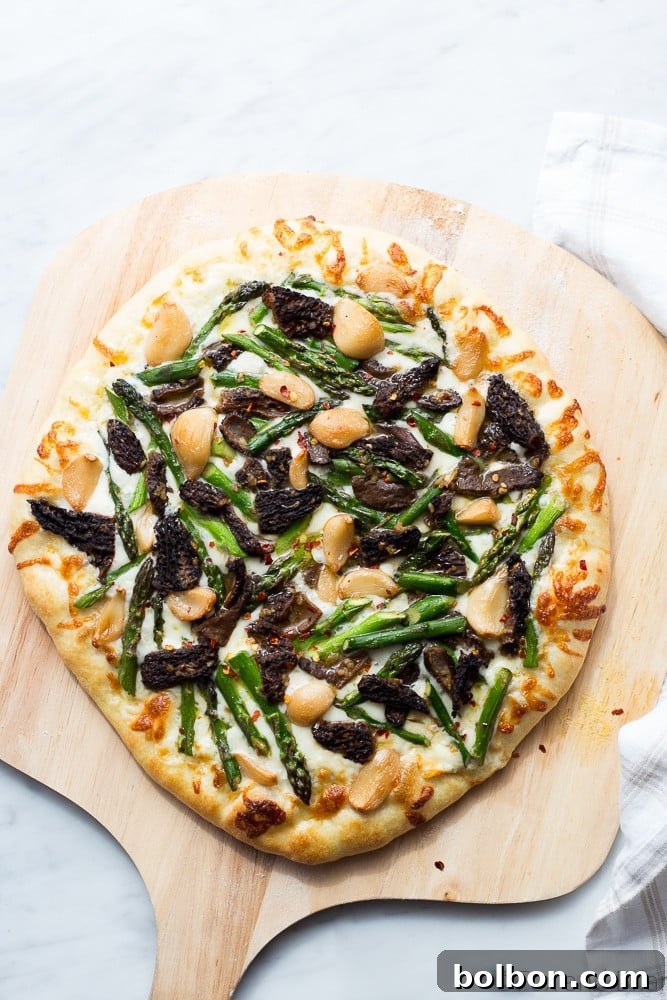Asparagus and Morel Pizza with Garlic Confit, a close-up of a slice revealing the fresh ingredients and golden crust.