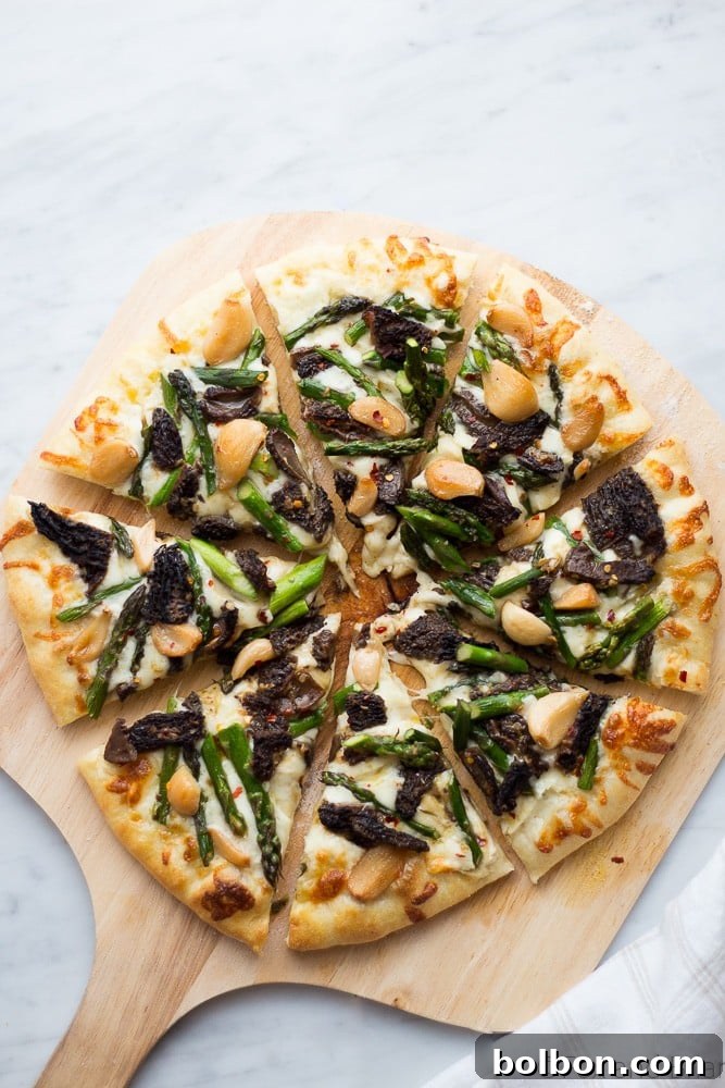 A pizza peel loaded with an unbaked Asparagus and Morel Pizza, ready for transfer to the hot stone.